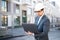 An architect / civil engineer at work on a construction site, holding plans in hand