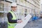 An architect / civil engineer at work on a construction site, holding plans in hand