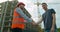 Architect contractor shaking hands with client at construction site.