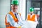 Architect in hard hat standing with blueprint in office corridor