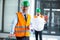 Architect in hard hat standing with blueprint in office corridor