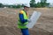 Architect looks at a drawing of a construction project, in an open area, prepared soil