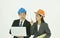 Architect man and woman wearing colorful helmet diccusing for work in whitre background