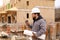 Architect speaking by walkie talkie and holding drawing plan at construction site.