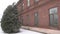 Architectural old red brick building on the background of Christmas trees, winter is snowing and the wind is blowing