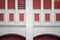 Architectural symmetric detail of old classy building with windows with red shutters and arches