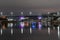 Architecture of the city in the light of night lighting. The city bridge over the river is illuminated by colorful lanterns