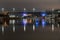 Architecture of the city in the light of night lighting. The city bridge over the river is illuminated by colorful lanterns