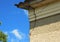 Architecture detail of damaged house corner dilapidated old building facade wall over blue sky background.