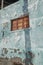 Architecture of an old blue wall with peeling paint outside. Exterior texture details of an old rustic residential build