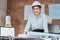 Architecture woman read blueprints design plan on the table and wearing safety helmet in room at site construction. Architecture,