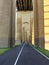 Archway corridor. Row of columns as a long tunnel with a road. Biker and jogger