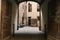 Archway in Siena Centro with a big wooden door exit to a small yard with a parked gray moped