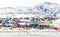 Arctic city center panorama with colorful Inuit houses on the rocky hills covered in snow with snow and mountain in the background