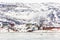 Arctic city panorama with colorful Inuit cottages and oil factory on the rocky hills covered in snow and mountain in the