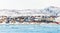Arctic city panorama with colorful Inuit houses on the rocky hills covered in snow with snow and mountain in the background and b