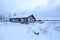 arctic log cabin covered by drifting snow