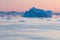 Arctic nature landscape with icebergs in Greenland icefjord with midnight sun sunset / sunrise in the horizon.  Early morning