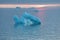 Arctic nature landscape with icebergs in Greenland icefjord with midnight sun sunset / sunrise in the horizon.  Early morning