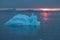 Arctic nature landscape with icebergs in Greenland icefjord with midnight sun sunset / sunrise in the horizon.  Early morning