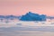 Arctic nature landscape with icebergs in Greenland icefjord with midnight sun sunset / sunrise in the horizon.  Early morning