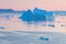 Arctic nature landscape with icebergs in Greenland icefjord with midnight sun sunset / sunrise in the horizon.  Early morning