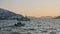 Arctic ship with people watching for two migrating humpback whales. Amazing winter fjord view at golden sunset