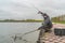 Area trout fishing. Fisherman with spinning rod in action playing fish