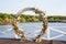 Area of the wedding ceremony in forest, near river on the pier. Wooden round arch. Cute, trendy rustic decor