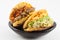 Arepas filled with shredded beef and pork rind served in a black ceramic dish