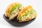 Arepas filled with shredded chicken and avocado served in a black ceramic dish