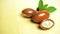 Argan nuts with green leaves motion on wooden background.