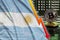 Argentina flag and falling red arrow on bitcoin mining screen and two physical golden bitcoins