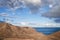 Arid coastal scenery against sky and ocean