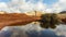 Arid dirt area with an expanse of crystal clear water reflecting the majestic mountain range.