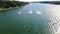 An Ariel dolly of 8 boats in groups in a head on POV with wakes spreading and crossing behind them on a recreational Reservoir Lak