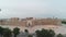 Ark of old Bukhara city fortress panorama filmed by drone from front gate on a warm cloudy day.