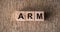 ARM Advanced RISC Machines word written on wooden blocks on a brown background