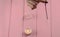 Arm of a dowser with hand-held pendulum on a chain with a natural crystal on a background of pink wood texture