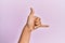 Arm and hand of caucasian young man over pink isolated background gesturing hawaiian shaka greeting gesture, telephone and