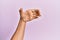 Arm and hand of caucasian young man over pink isolated background holding invisible object, empty hand doing clipping and grabbing