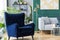 Armchair next to grey scandinavian sofa in tropical inspired interior with green and gold colors