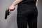 Armed girl in black jeans hides her pistols gun behind her back. Hidden threat Killer woman.