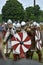 Armed knights in chain mail, helmets and red-white shields perform a combat structure at the historic festival of