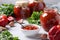 Armenian adjika from red pepper, tomatoes, garlic, cilantro and parsley in a bowl and jars, as well as fresh ingredients on a