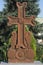 Armenian cross. Sculpture. In the park. Against the backdrop of green trees and sky. Surb Khach