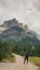 Armentarola - A man with a hiking backpack hiking on a gravelled road in high Italian Dolomites. There is a dense forest