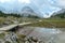 Armentarola - A small pond under a wooden bridge in Italian Dolomites. The pond is reflecting the surrounding mountains