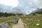 Armentarola - A woman with a hiking backpack hiking on a gravelled road in high Italian Dolomites. There is a dense forest