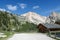 Armentarola - Wooden cottages along a gravelled road in Italian Dolomites. The cottage is surrounded by sharp mountain chain